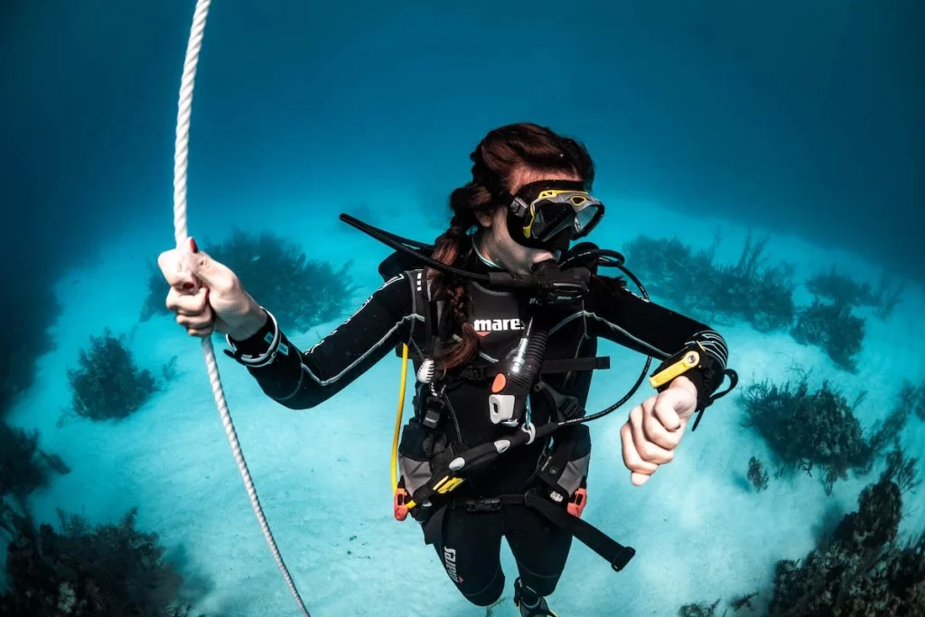 Divers monitor dive computers underwater while following conservative depth and time limits