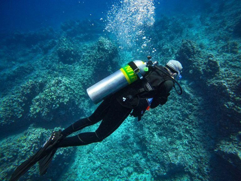 Scuba divers underwater carrying clearly marked enriched air nitrox cylinders